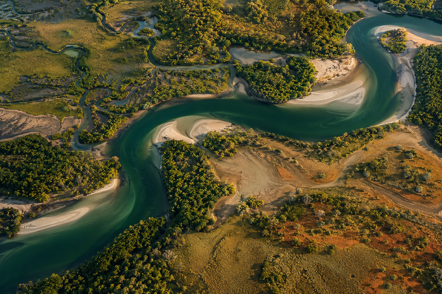 A winding river through green Australian wetlands and sandy Country